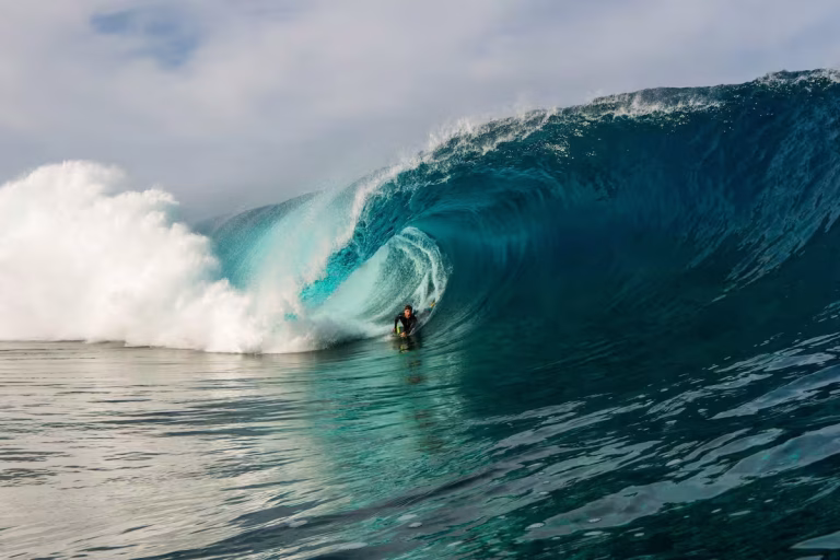 Bodyboarder dentro del tubo de una ola turquesa