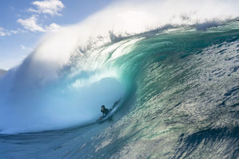 Bodyboarder surfeando una ola azul con espuma en el mar